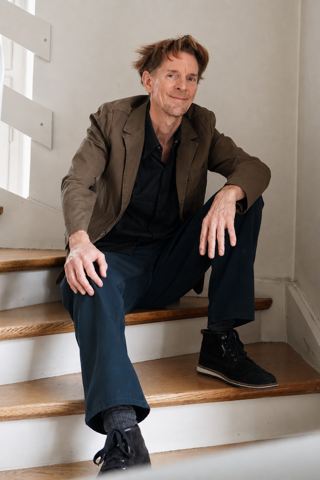 Sascha Markus Huth seated on a wooden staircase — artist portrait